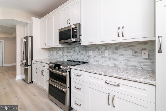 kitchen with light stone countertops, appliances with stainless steel finishes, white cabinets, and backsplash