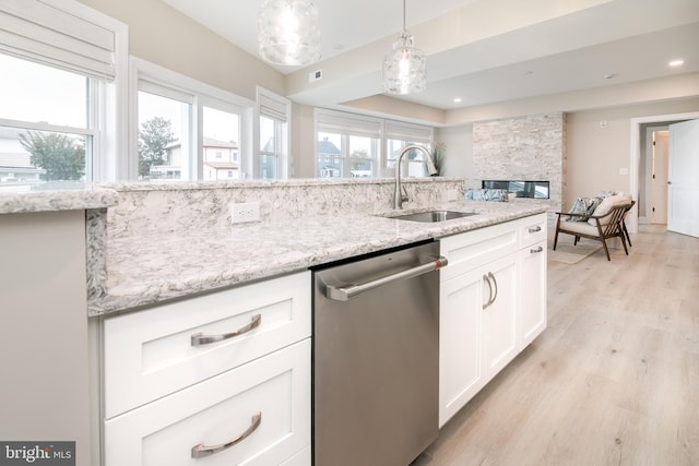 kitchen with dishwasher, sink, white cabinets, hanging light fixtures, and light wood-type flooring