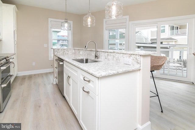 kitchen with white cabinetry, stainless steel appliances, sink, and a center island with sink