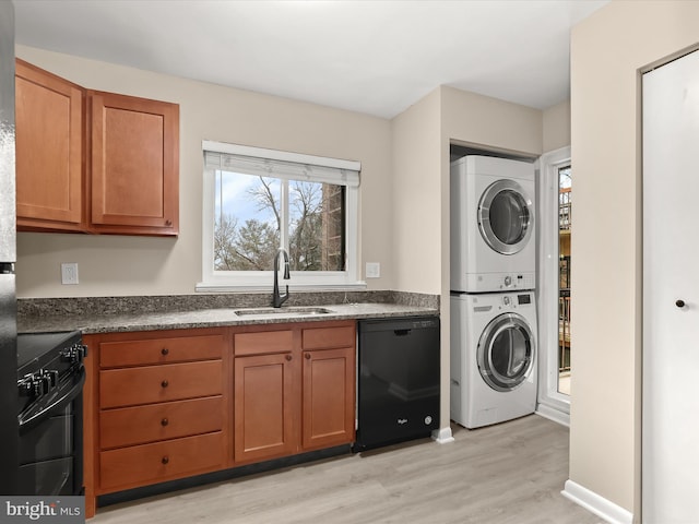 clothes washing area featuring stacked washer / dryer, sink, and light wood-type flooring