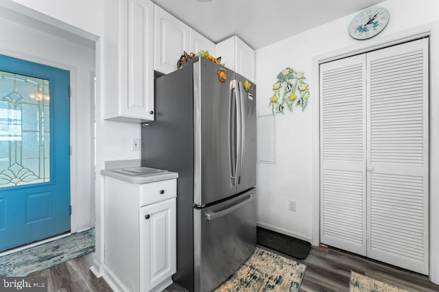 kitchen featuring stainless steel fridge, dark hardwood / wood-style flooring, and white cabinets