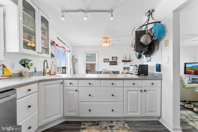 kitchen with sink, dark wood-type flooring, stainless steel dishwasher, and white cabinets