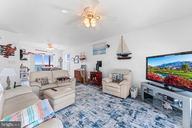 living room featuring ceiling fan and a wood stove