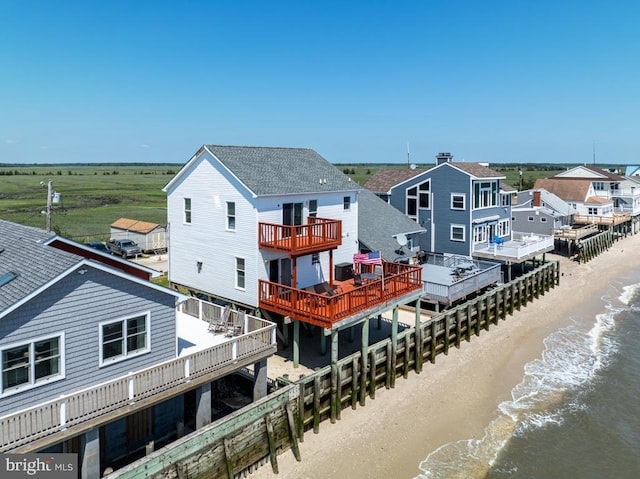 back of house featuring a water view and a view of the beach