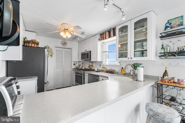 kitchen with white cabinetry, sink, ceiling fan, kitchen peninsula, and stainless steel appliances