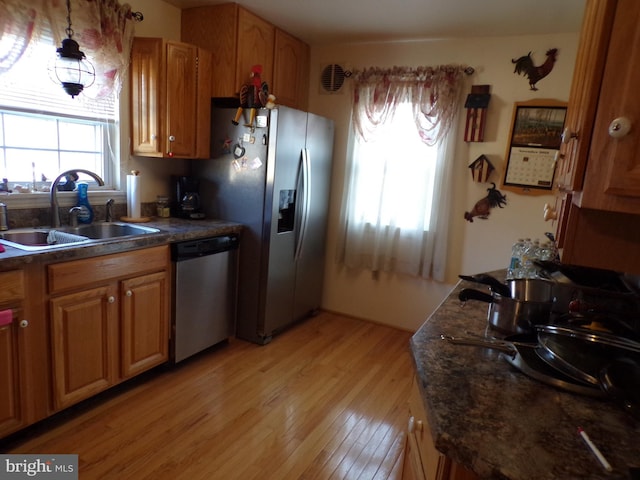 kitchen with appliances with stainless steel finishes, decorative light fixtures, light hardwood / wood-style floors, and sink