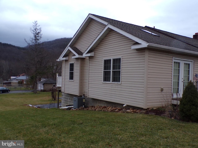 view of side of home with cooling unit and a lawn