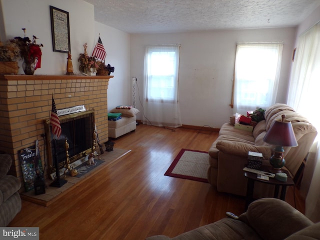 living room with hardwood / wood-style flooring, a textured ceiling, and a fireplace