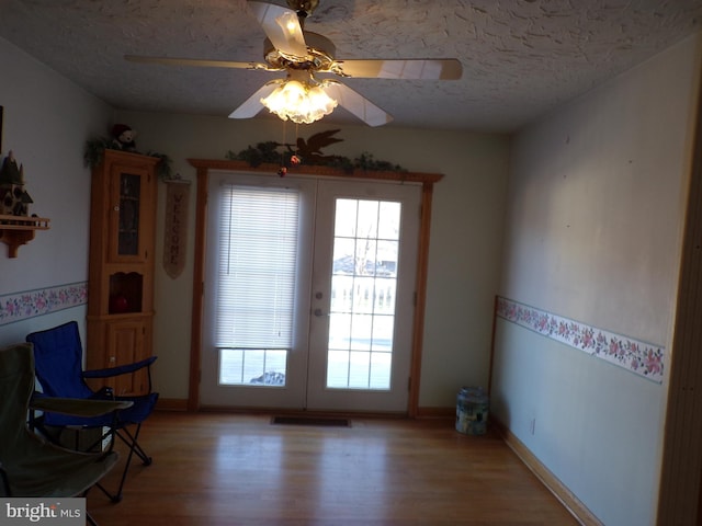 interior space with french doors, ceiling fan, wood-type flooring, and a textured ceiling