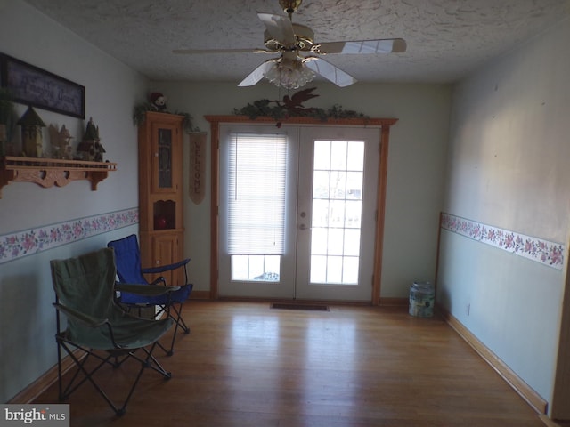 unfurnished room featuring french doors, ceiling fan, light hardwood / wood-style floors, and a textured ceiling