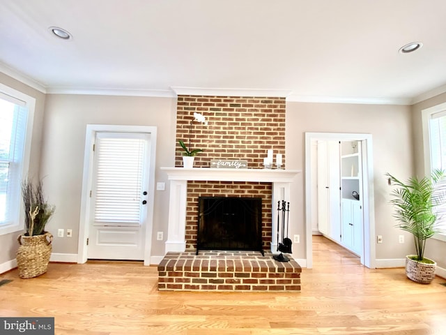 living room with crown molding, a brick fireplace, and light hardwood / wood-style flooring