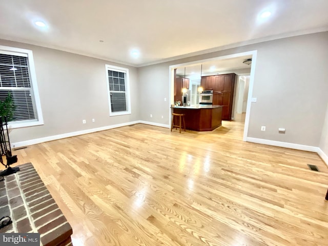 unfurnished living room featuring crown molding and light hardwood / wood-style floors