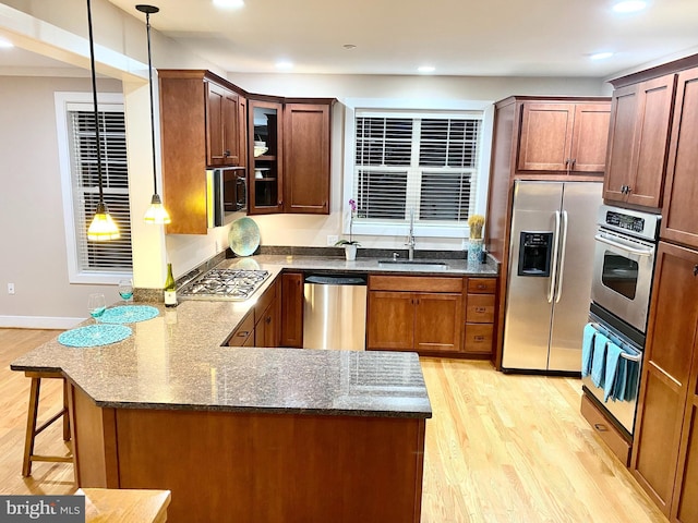 kitchen with sink, decorative light fixtures, kitchen peninsula, and appliances with stainless steel finishes