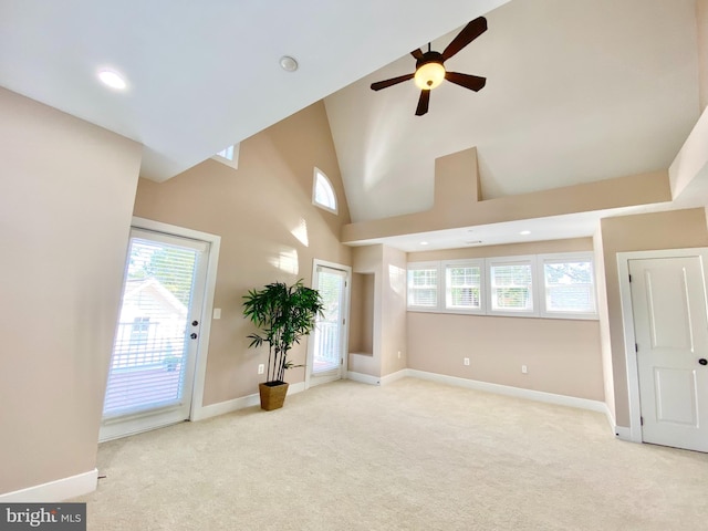 empty room with a high ceiling, light carpet, and ceiling fan