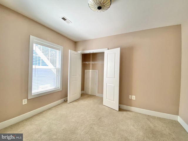 unfurnished bedroom with light colored carpet and a closet