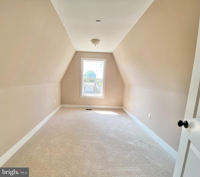 bonus room with lofted ceiling and light carpet