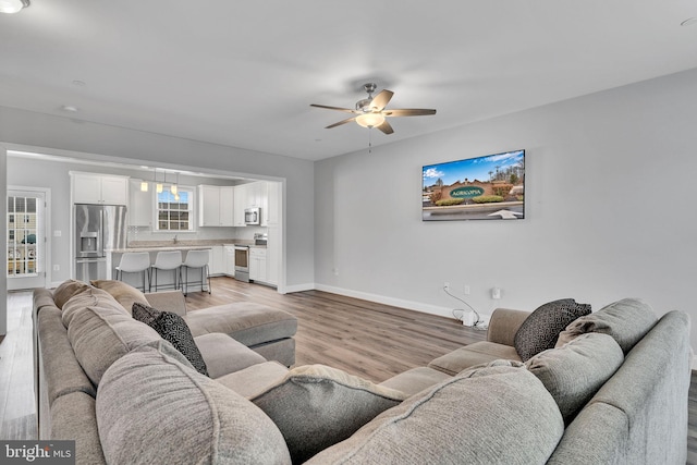 living room with sink, light hardwood / wood-style flooring, and ceiling fan