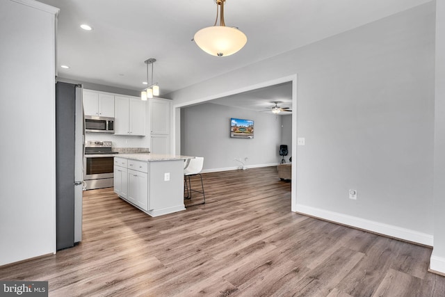 kitchen featuring stainless steel appliances, decorative light fixtures, a kitchen island, and white cabinets