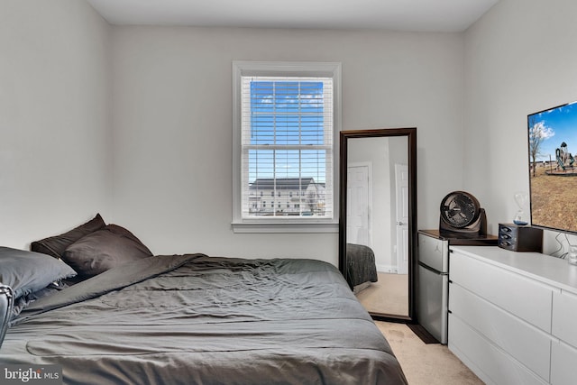 bedroom with stainless steel refrigerator and light colored carpet