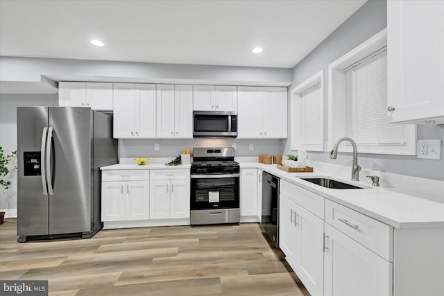 kitchen featuring white cabinetry, stainless steel appliances, sink, and light wood-type flooring