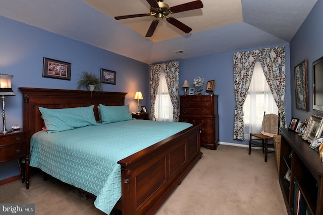 carpeted bedroom featuring ceiling fan and a tray ceiling