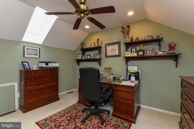 carpeted office featuring lofted ceiling with skylight and ceiling fan