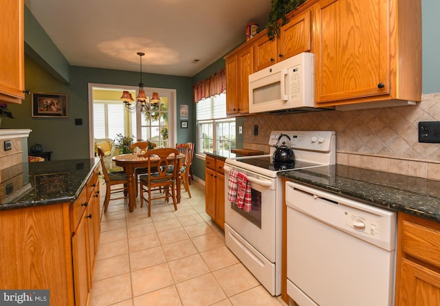 kitchen featuring light tile patterned floors, white appliances, hanging light fixtures, backsplash, and dark stone counters