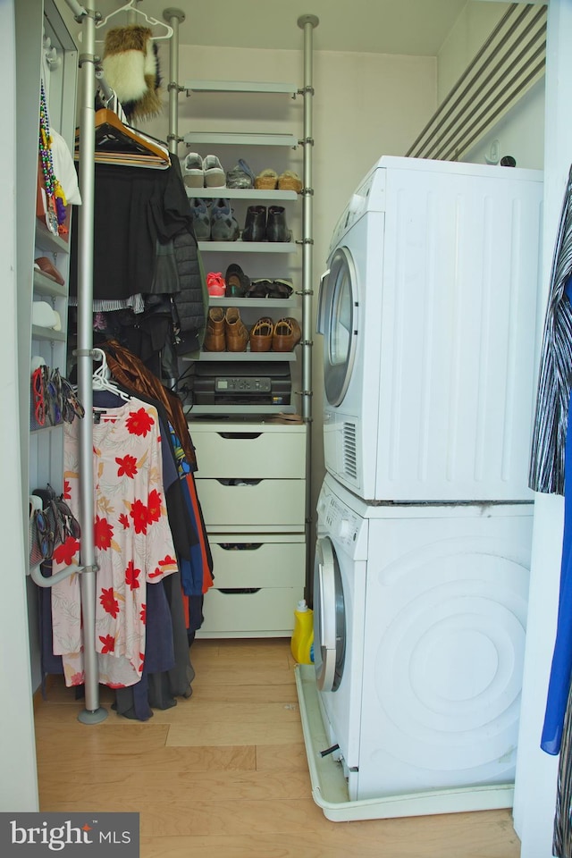 washroom with stacked washer / dryer and wood finished floors