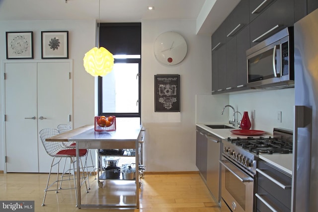 kitchen with a sink, stainless steel appliances, light wood-style flooring, dark cabinets, and modern cabinets