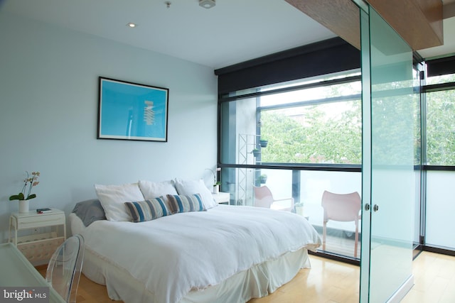 bedroom with multiple windows, light wood-style floors, and expansive windows