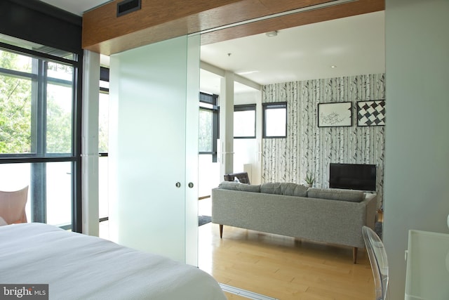 bedroom featuring a fireplace, wood finished floors, visible vents, and multiple windows