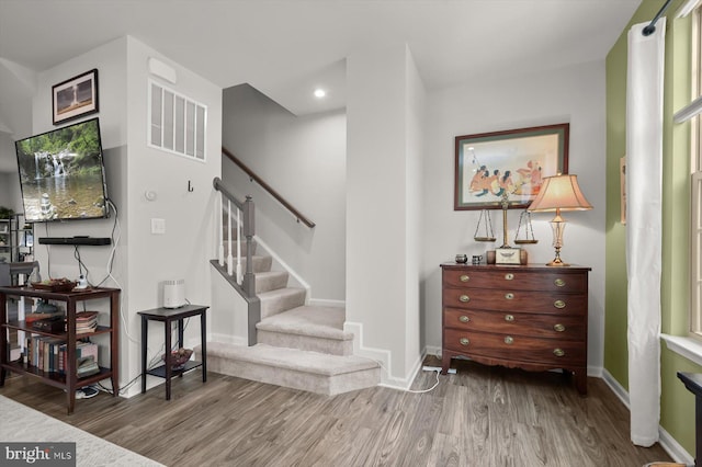 stairway with wood finished floors, visible vents, and baseboards