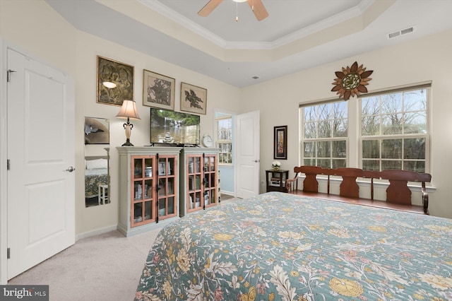 bedroom featuring crown molding, a raised ceiling, light colored carpet, visible vents, and baseboards