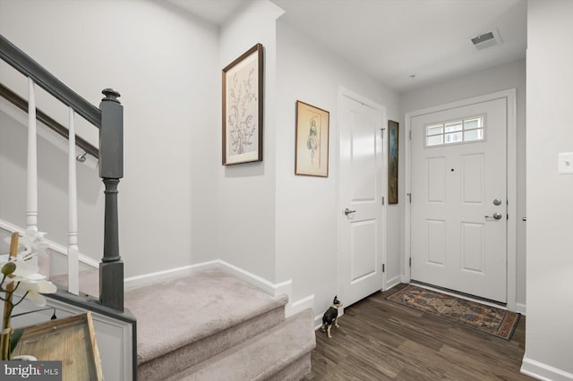 foyer with stairs, dark wood-style flooring, visible vents, and baseboards