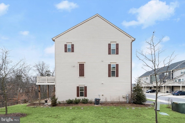 back of house with a balcony, central AC unit, and a yard