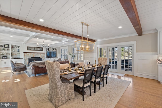 dining space featuring a fireplace, light hardwood / wood-style floors, a chandelier, and beamed ceiling