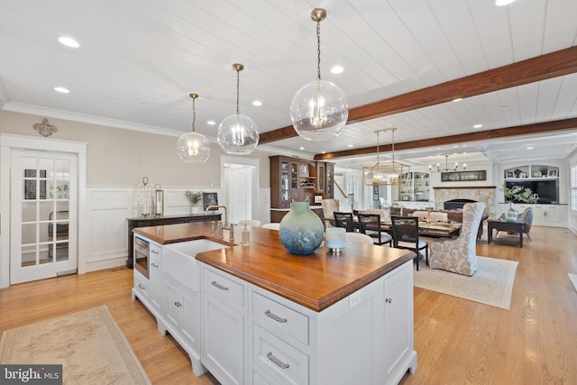 kitchen featuring white cabinetry, a center island with sink, beam ceiling, and decorative light fixtures