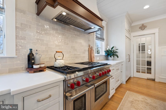 kitchen featuring range with two ovens, ornamental molding, custom range hood, white cabinets, and light wood-type flooring