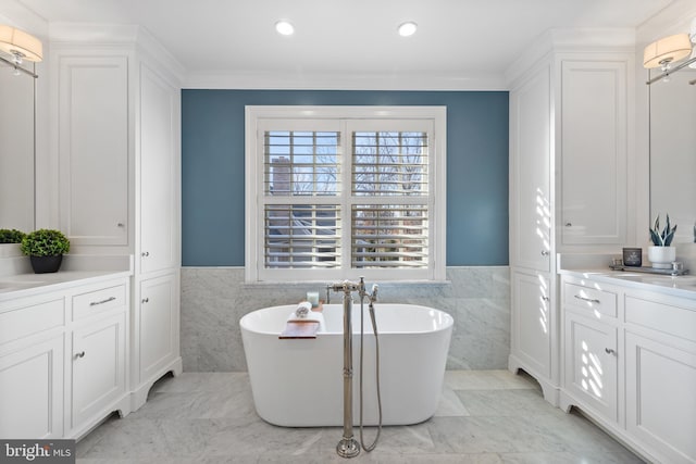 bathroom featuring vanity, a bath, crown molding, and tile walls