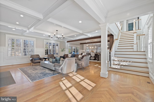 living room featuring an inviting chandelier, coffered ceiling, ornamental molding, beamed ceiling, and ornate columns