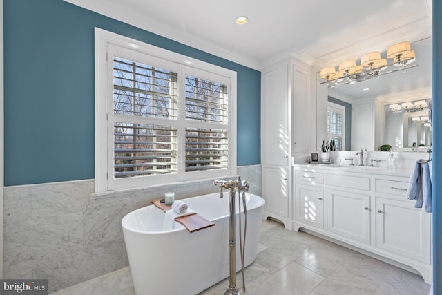 bathroom with vanity, a tub to relax in, ornamental molding, and tile walls