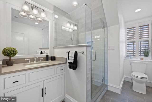 bathroom featuring tile patterned floors, vanity, toilet, and a shower with shower door