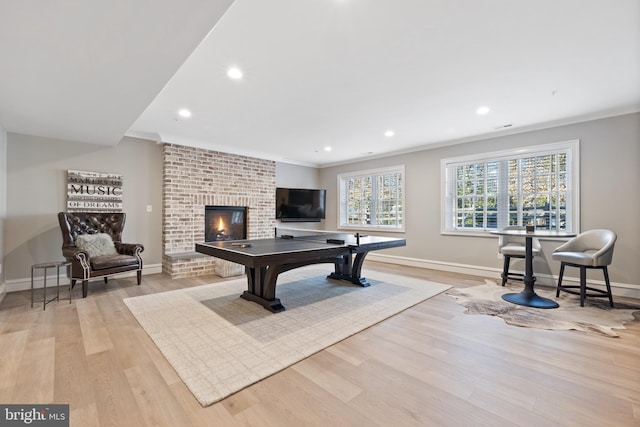 recreation room with ornamental molding and light hardwood / wood-style flooring