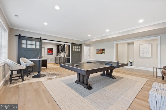 playroom with crown molding, a barn door, and light hardwood / wood-style floors