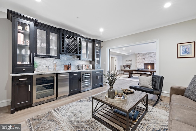 interior space with tasteful backsplash, beverage cooler, light stone counters, and light hardwood / wood-style floors