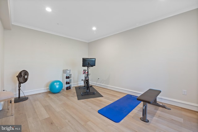 workout area featuring crown molding and light wood-type flooring