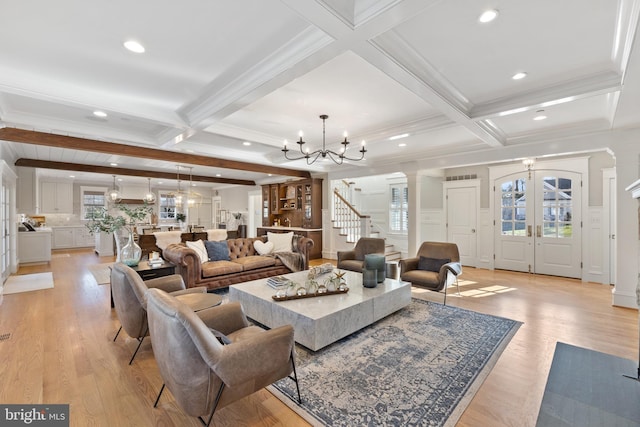 living room with beamed ceiling, ornamental molding, light wood-type flooring, and a notable chandelier