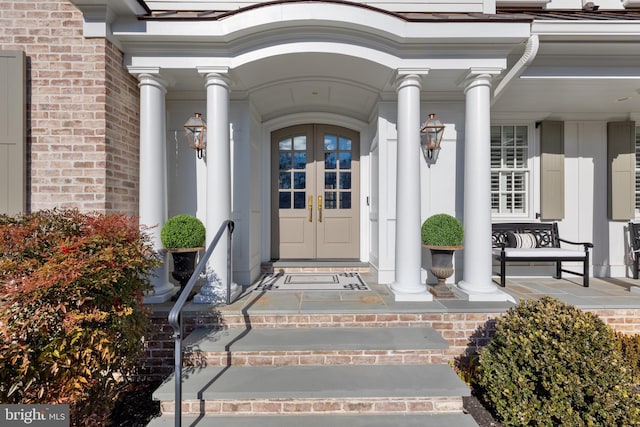 view of exterior entry featuring french doors and a porch