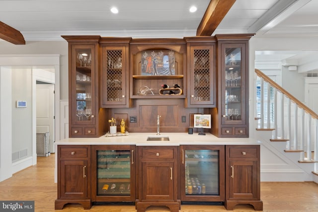 bar with wine cooler, sink, light hardwood / wood-style flooring, and beamed ceiling