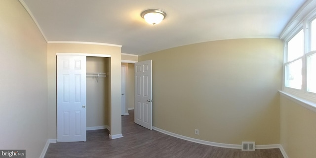 unfurnished bedroom with a closet, ornamental molding, and dark hardwood / wood-style floors